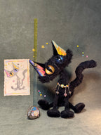 The Halloween black cat photographed beside a ruler for scale