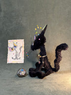 Side view of the black cat art doll and its hanging beaded accessories