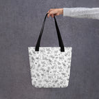 Printful mockup of the Yizcho Cat Parade tote held by a hand in a grey sleeve.