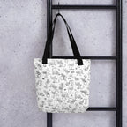 Printful lifestyle mockup of the Yizcho Cat Parade tote hanging from a black ladder.